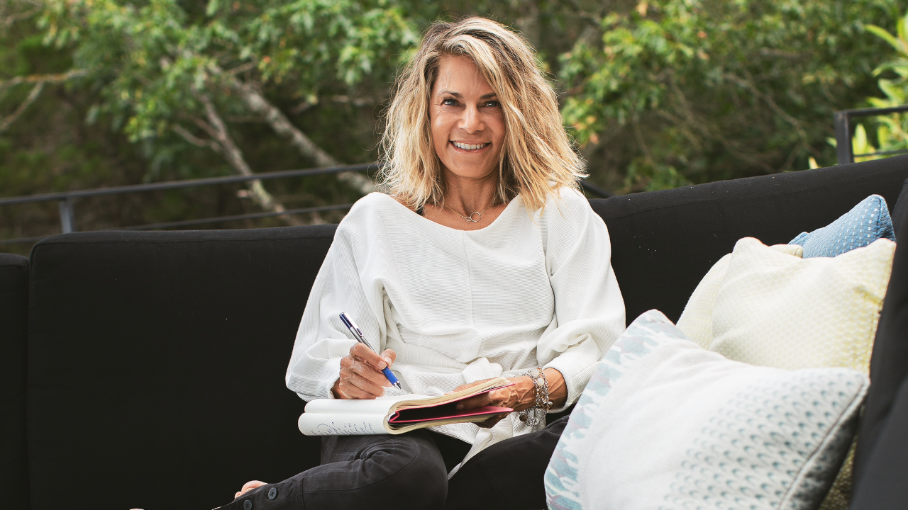 Krisstina Wise smiling while writing in a journal